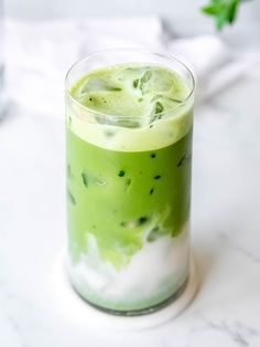 a glass filled with green liquid on top of a table