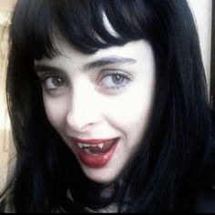 a close up of a person with long black hair and red lipstick on her face