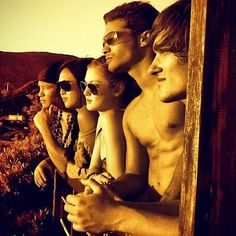 a group of people standing next to each other in front of a wooden structure with mountains behind them