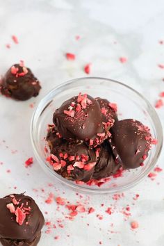 chocolate covered cookies in a glass bowl with red sprinkles on the side