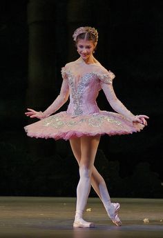 a young ballerina is dressed in pink and white