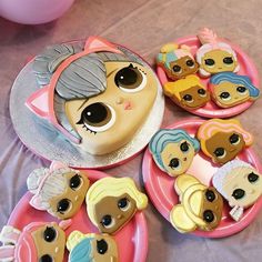 there are many little dolls on the pink plates and one has a cake in the shape of a face