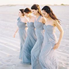 bridesmaids in blue dresses walking on the beach at sunset photo by wedding photographer