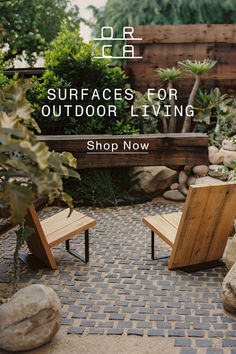 two wooden benches sitting on top of a stone walkway next to trees and bushes with the words surfaces for outdoor living shop now