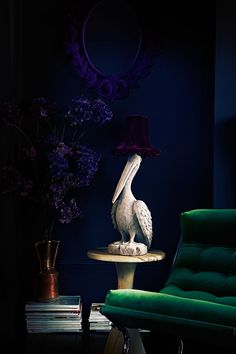 a pelican statue sitting on top of a table next to a green chair