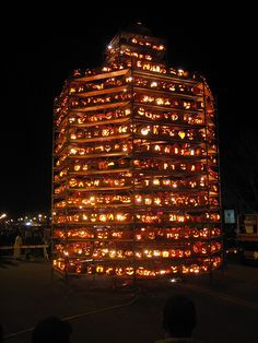 a tall tower with lots of pumpkins on it's sides and lights in the windows