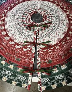 a large christmas tree skirt made with red, green and white fabric on top of a table