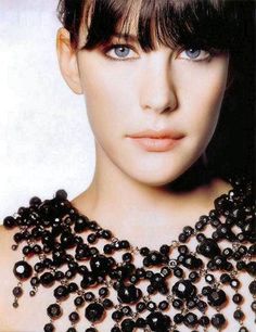 a woman wearing a black beaded necklace with lots of beads on her neck and shoulders