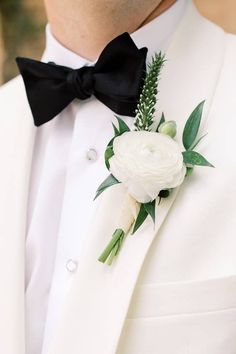 a man in a tuxedo wearing a flower boutonniere and a black bow tie