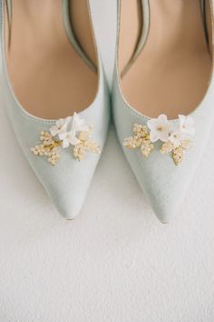 the bride's shoes are adorned with flowers and gold brooches, which she chose for her wedding day