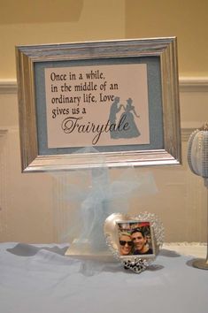 a table topped with a framed photo next to a couple's wedding cake topper