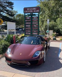 a red sports car parked in front of a sign