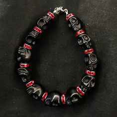 "If you're like me, you love skulls. So show your love with this skull bracelet! This bracelet features black howlite stone skulls and red stone crystal spacers, and is closed with a silver stainless steel lobster claw clasp. It comes in 3 sizes: Large - Fits wrists you to 7 1/2\" around Medium - Fits wrists up to 6 1/2\" around Small - Fits wrists up to 5 1/2\" around. If you need a different size, let me know and I will see what I can do. Make sure to check out my shop, PopBangBoom, for all so Black Gothic Skull Bracelet, Black Gothic Bracelets With Skull Print, Black Rock Style Bracelet For Gift, Black Beaded Gothic Bracelets, Gothic Black Beaded Bracelets, Punk Style Black Beaded Bracelets For Gift, Emo Black Skull Jewelry, Black Rock Style Jewelry For Halloween, Gothic Black Beaded Bracelets For Halloween