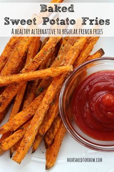 some french fries and ketchup on a white plate with a small glass bowl