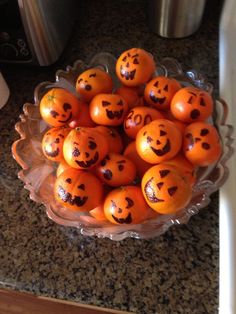 a bowl full of oranges with faces drawn on them