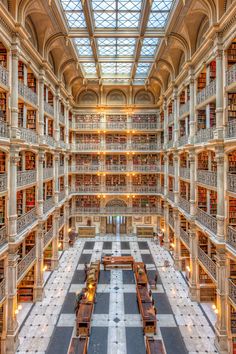 the inside of a library with many bookshelves and tables on each floor, looking up at the skylight