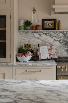 a kitchen with marble counter tops and gold trimming on the cabinets, along with a bowl of fruit