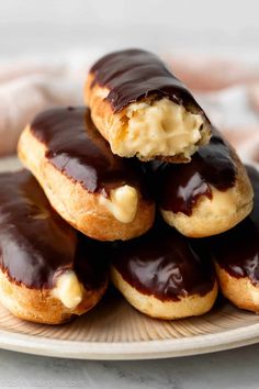 chocolate covered doughnuts stacked on top of each other with cream filling in the middle