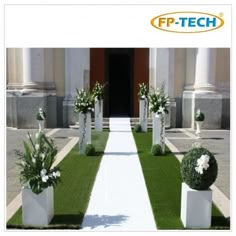 an outdoor ceremony with white flowers and greenery on the grass in front of a building