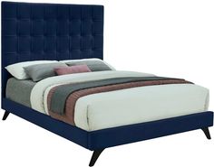 a bed with blue upholstered headboard and pillows