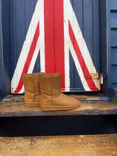 a pair of brown boots sitting on top of a wooden bench next to a flag