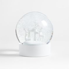 a snow globe with white frosting on the top and two figures in it, sitting on a stand