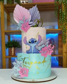 there is a cake decorated with flowers and lillies on the bottom tier, which has an image of stitch