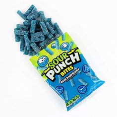 a bag of soury punch bites sitting on top of a white table next to a pile of blue candy