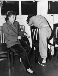 two women are sitting in chairs and one has her foot on the chair's leg