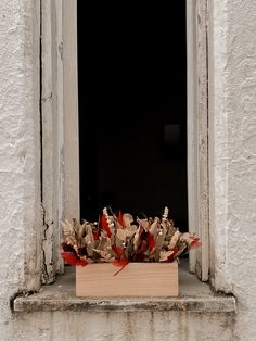 a wooden box filled with leaves sitting on top of a window sill in front of a white building