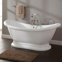 a white bath tub sitting on top of a bathroom floor next to a brown rug