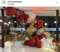 balloons and decorations are displayed in front of a window at an indoor event with the number fifteen on it