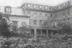 an old black and white photo of a building with flowers in the foreground,