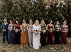 a group of women standing next to each other in front of trees and leaves on the ground