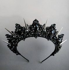 a black tiara with spikes and stones on it's headband, against a gray background