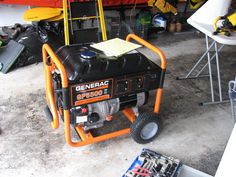 an orange and black generator sitting on top of a floor next to other items in a garage