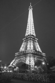 the eiffel tower lit up at night in black and white, with its lights on