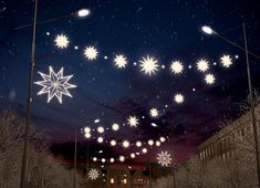 snowflakes are flying in the night sky over trees and street lights on poles