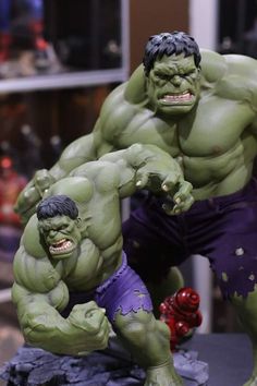 two action figures that are on display in a store window, one is green and the other is purple