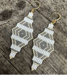 two pairs of beaded earrings sitting on top of a wooden table