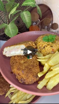 a pink plate topped with fried food next to french fries and green leafy plants