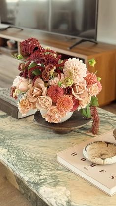 a vase filled with pink flowers sitting on top of a table next to a book