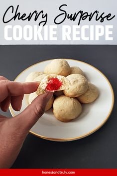 a person holding a cookie in their hand with the words cherry surprise on it and cookies behind them