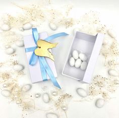 an open box with eggs in it and a blue ribbon around the inside is surrounded by pearls