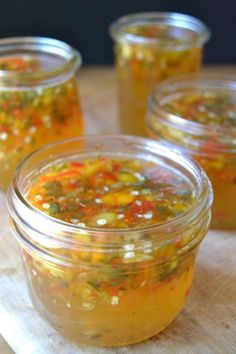 four jars filled with food sitting on top of a wooden table