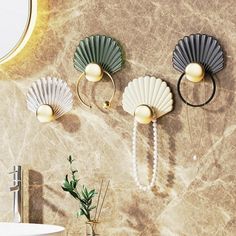 three seashells are hanging on the wall next to a white sink and mirror