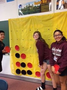 three girls are standing in front of a wall with frisbees on it