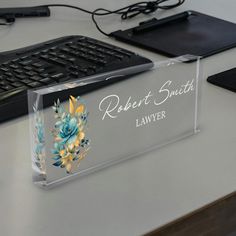 a clear acrylic business card holder sitting on top of a desk next to a keyboard