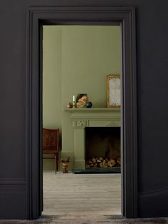 an open door leading to a living room with fireplace and chair in it's center