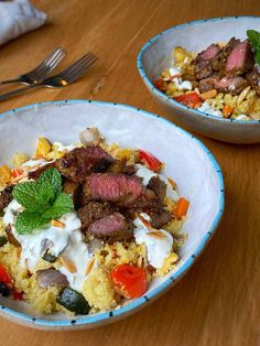 two bowls filled with food on top of a wooden table